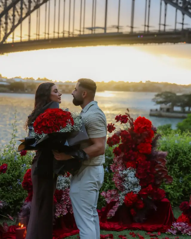 Newly engaged couple surrounded by red flowers