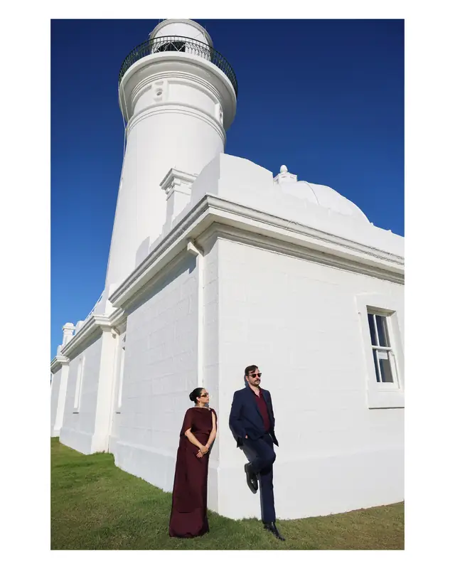 Negin and Alex photographed beside a white lighthouse